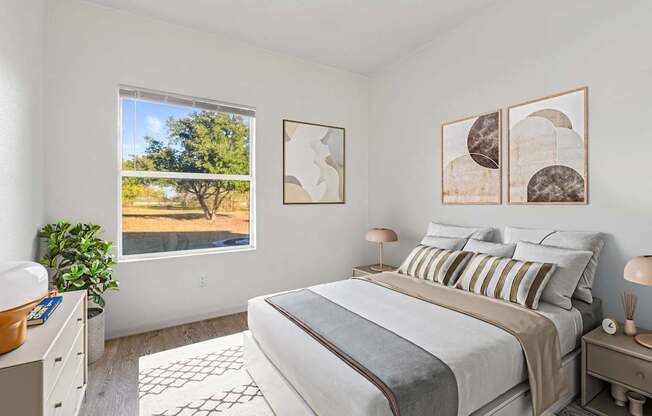 Pet-Friendly Apartments in Austin, TX – Huntington Meadows – A bedroom with a large bed and a window overlooking a tree.