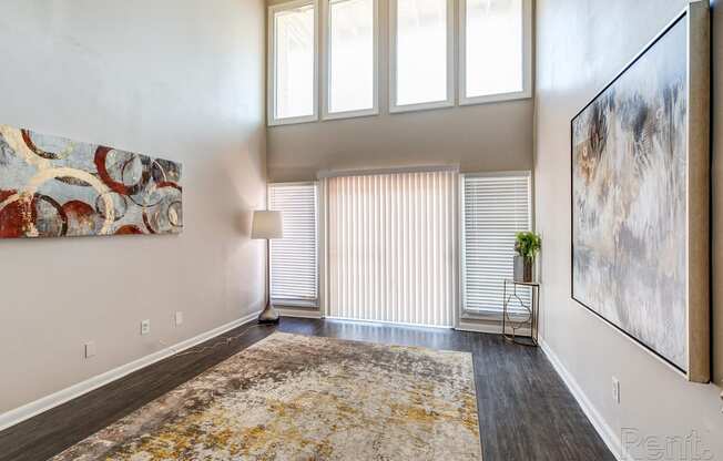 an empty living room with high ceilings and a window with blinds