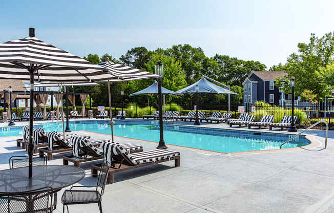 a swimming pool with chaise lounge chairs and umbrellas