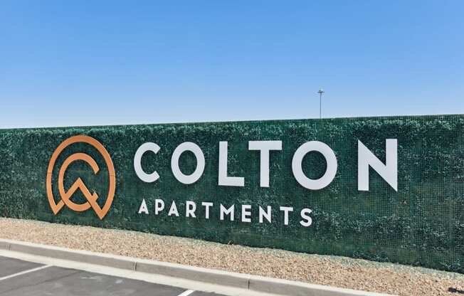 a green wall with the colton apartments logo on it