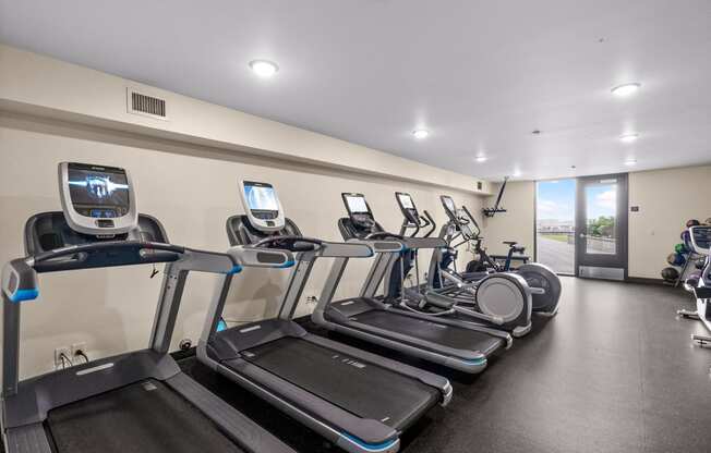 a gym with cardio equipment and a row of treadmills