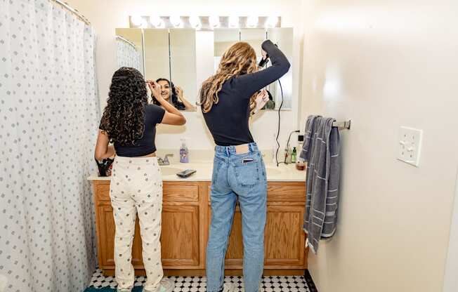two women doing their hair in a bathroom