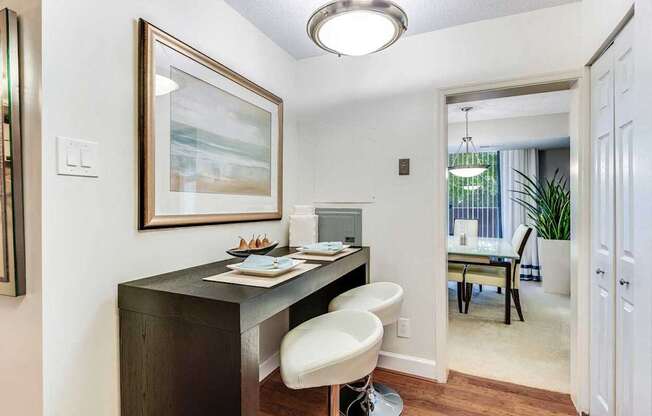 A home office with a desk, chair, and painting on the wall.