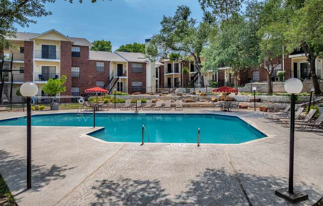 A swimming pool surrounded by apartment buildings and trees.