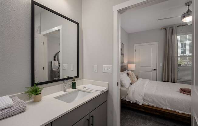 a bathroom with a mirror and a sink and a bedroom with a bed