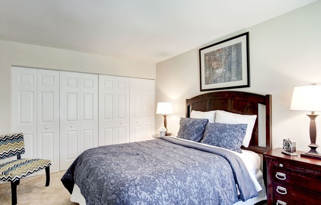 A bedroom with a bed, nightstand, and chair.