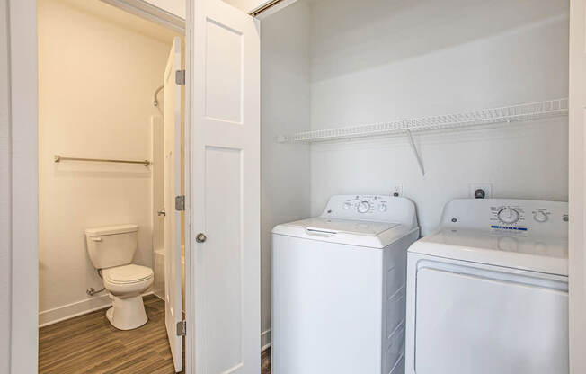 A laundry room with a full size washer and dryer and an adjacent bathroom at Meadowbrooke Apartment Homes in Kentwood, MI 49512
