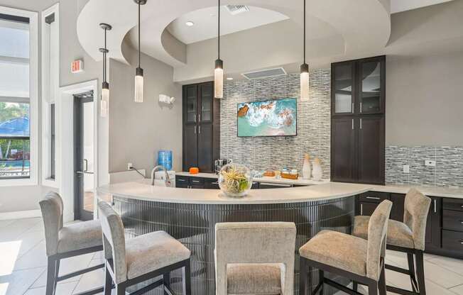 A kitchen with a large island and chairs around it.