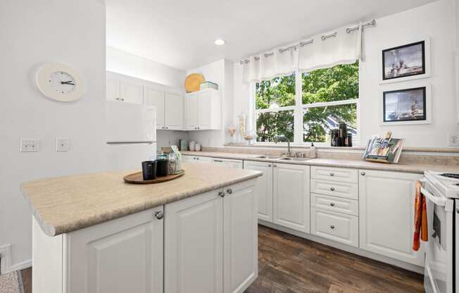 a kitchen with white cabinets and a large window