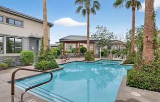 A swimming pool surrounded by palm trees and a building.