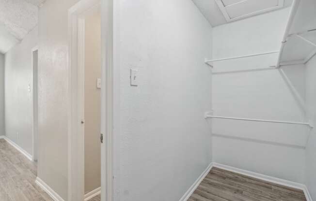 A walk-in closet of our A7 apartment The Escapade with white walls and wood flooring