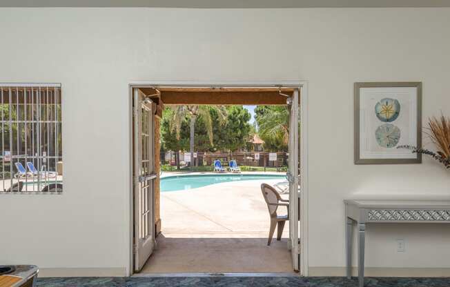 a view of a pool from a living room with a door open to a backyard