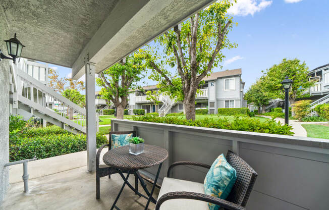 a patio with two chairs and a table on a balcony