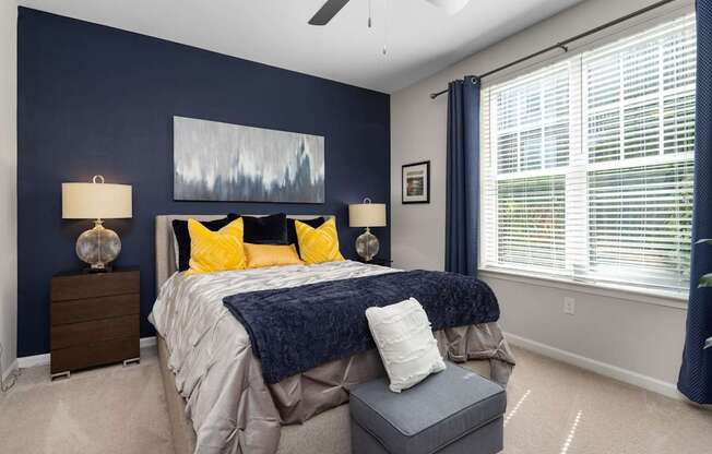 A bedroom with a bed, two lamps, and a painting on the wall.