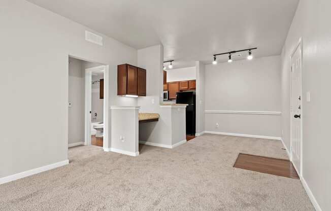 an empty living room with a kitchen with a sink and a window