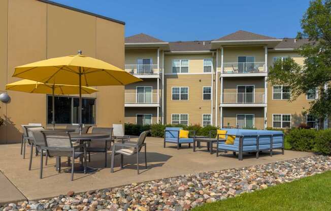 an outdoor patio with tables and umbrellas at chaska place apartments