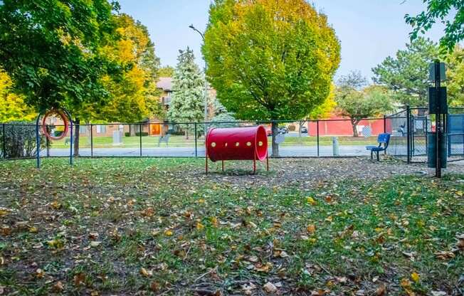 a playground with a red bench and trees in the background at Fifteen 98 Naperville, Naperville, IL