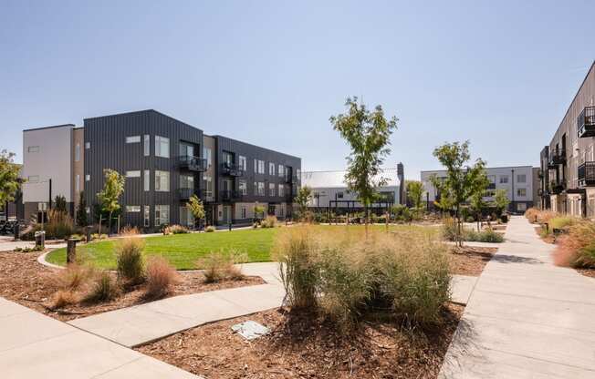 an exterior view of an apartment complex with a sidewalk and landscaping