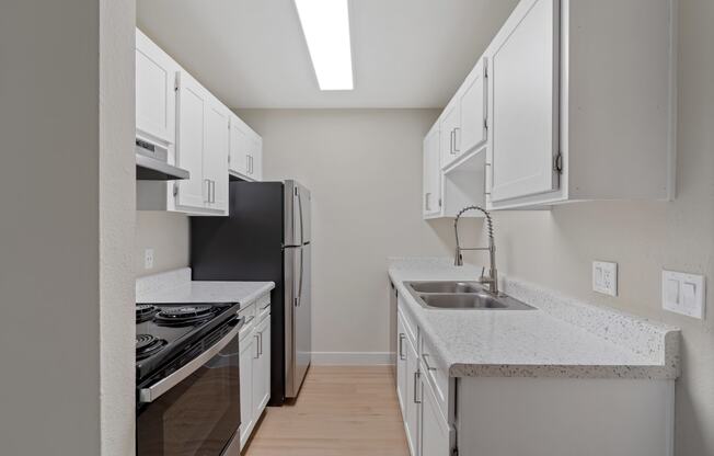 Kitchen with white cabinets and a sink and a refrigerator at Verde Apartments in Tucson, AZ