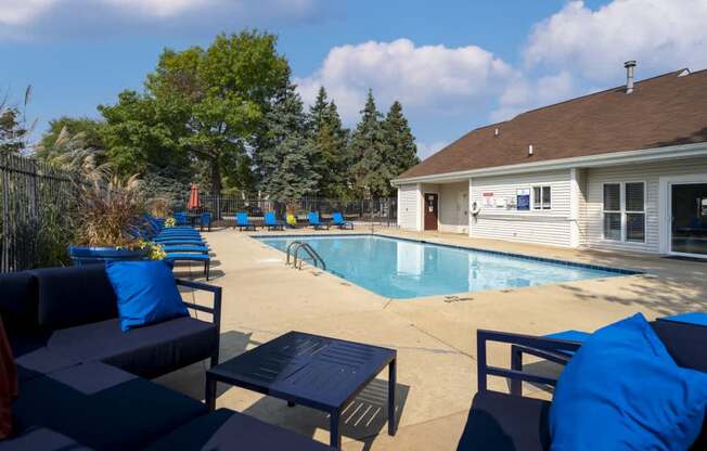 A pool area with blue cushions and a white building in the background.