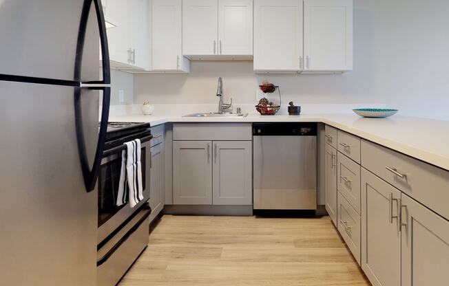 U-shaped kitchen with stainless steel oven, hood vent, dishwasher, sink, and fridge from left to right. at 3030 Lake City, Seattle, Washington