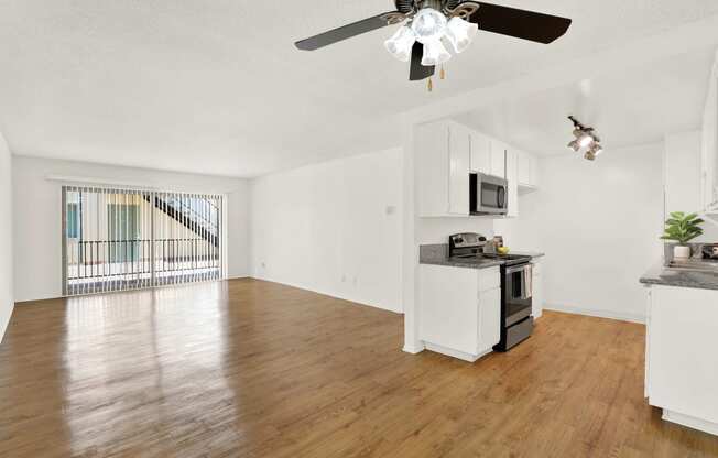 an empty living room with a kitchen and a ceiling fan at Casa Del Amo Apartments, Torrance