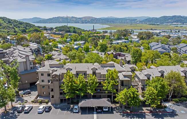 an aerial view of a building in a city with trees and a lake