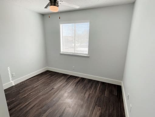 an empty room with wood flooring and a window