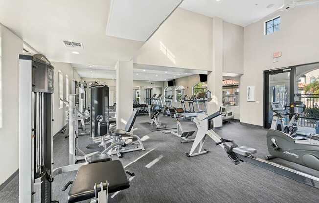 A gym with a variety of equipment including treadmills, weights, and exercise machines.