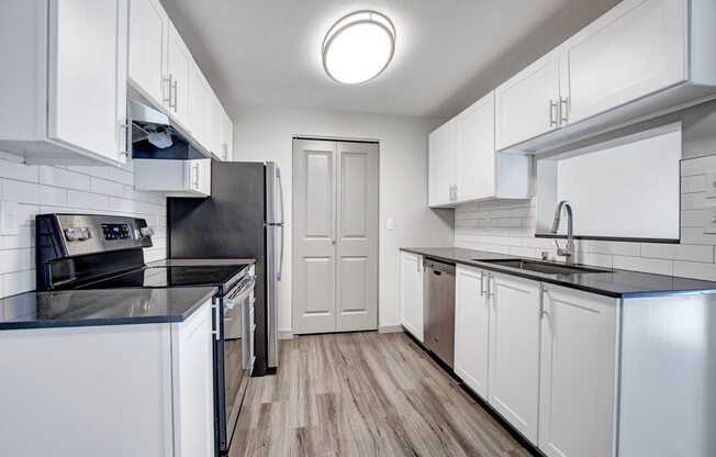 a kitchen with white cabinets and black counter tops