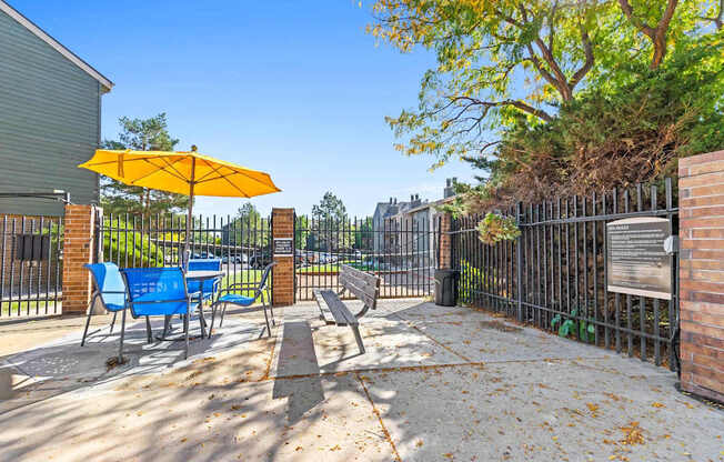 A yellow umbrella is on a blue chair on a patio.