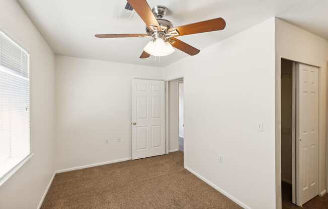 a bedroom with a ceiling fan and a door to a closet