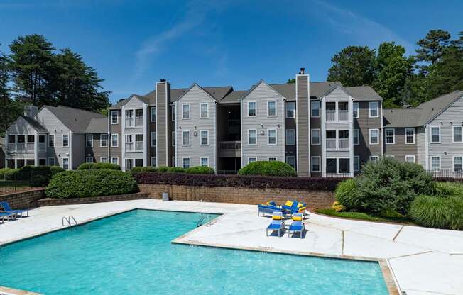 A swimming pool in front of a building with a blue sky in the background.