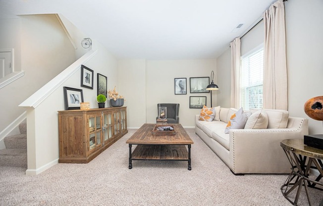 A living room with a couch, coffee table, and staircase.