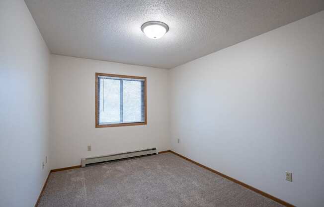 a bedroom with white walls and a window. Fargo, ND  Prairie Park Apartments