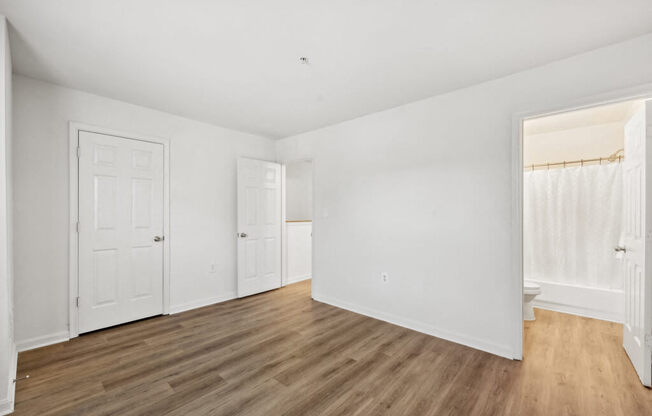 an empty living room with white walls and wood floors