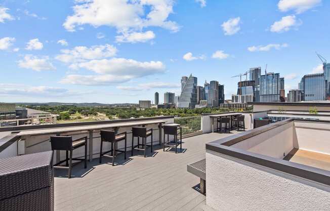 a rooftop terrace with tables and chairs and the city in the background