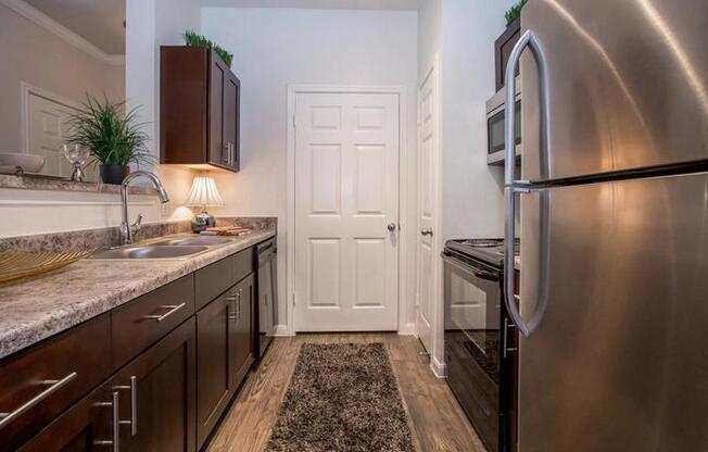 A kitchen with a stainless steel refrigerator and wooden cabinets.