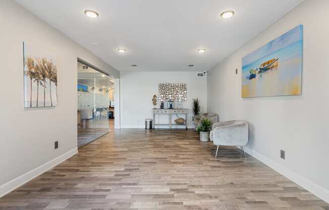 the living room with white walls and wood flooring and a white couch and chair