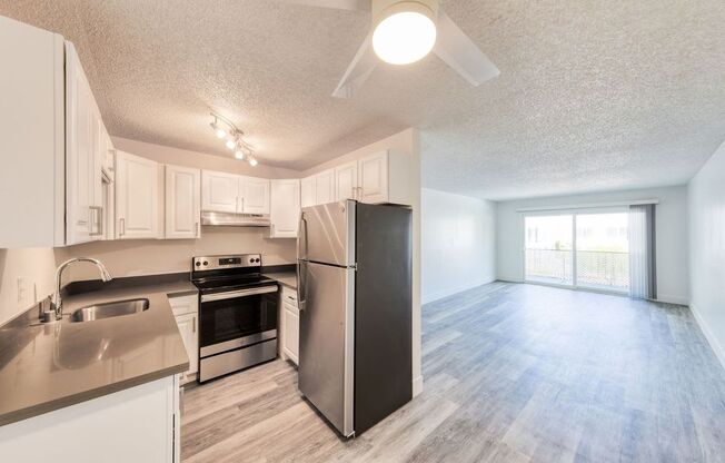 an empty kitchen and living room with a ceiling fan