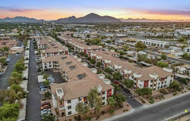 A sunset view of a residential area with apartment buildings and cars parked in the driveways.