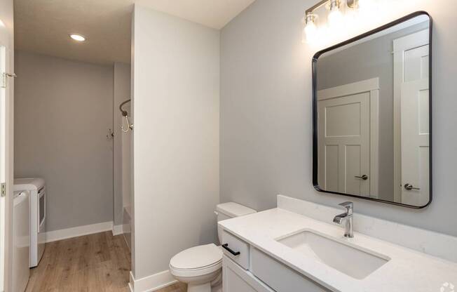 A white bathroom with a toilet, sink, and mirror.