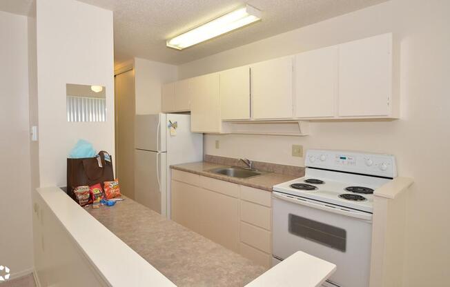 an empty kitchen with white appliances and white cabinets