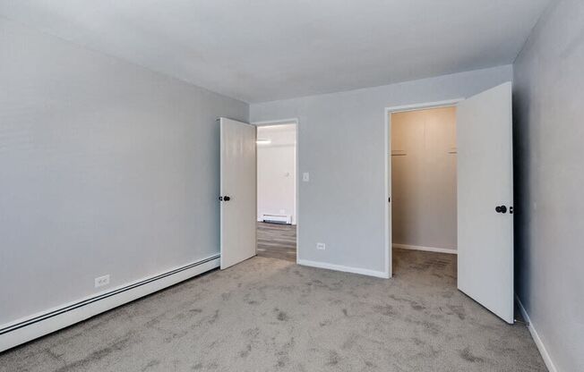 an empty bedroom with two doors and a carpeted floor