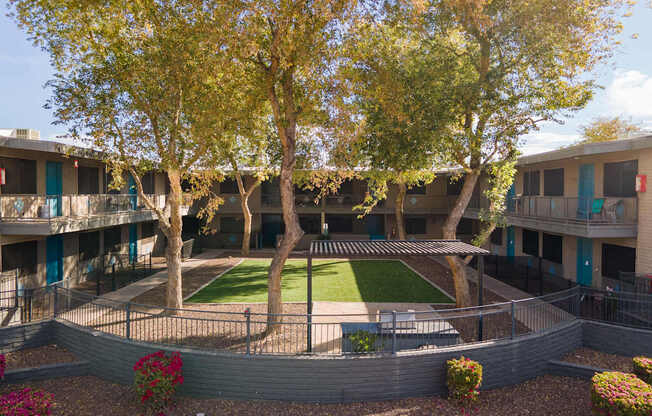 A courtyard with a lawn and trees.