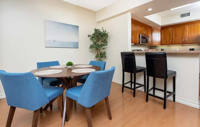 a dining area with a table and chairs and a kitchen in the background