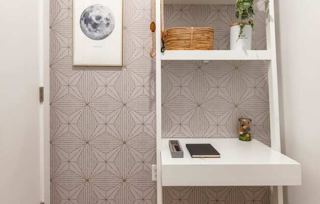 a small workspace with a white desk and a white shelf and a chair