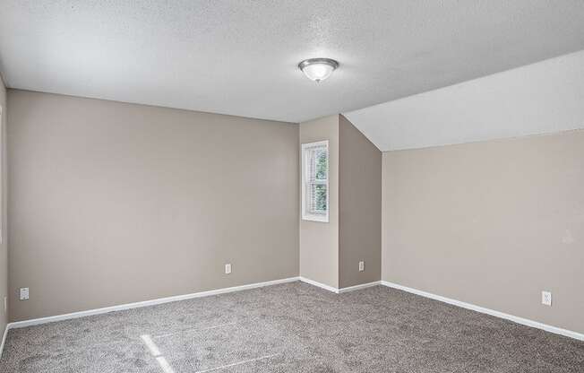 an empty living room with carpet and a light on the ceiling