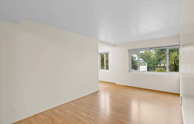 a living room with white walls and a window and wooden floors