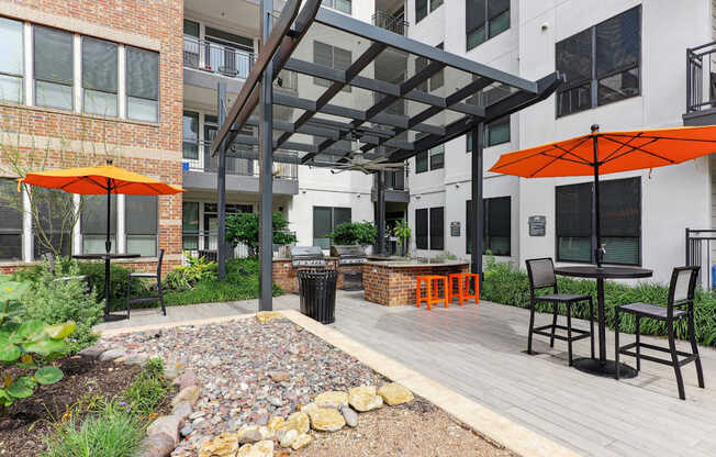 A patio with a table and chairs under an orange umbrella.